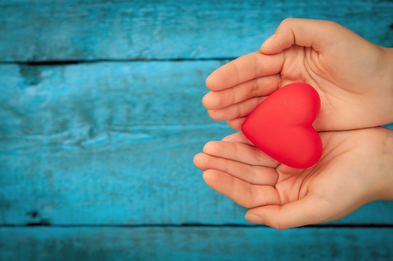 Valentine day. Red heart in the hands. Red heart on the blue boards. Valentine's Day. Heart pendant. Red heart.  Space for text. Eighth of March. International Women's Day. Toned image.